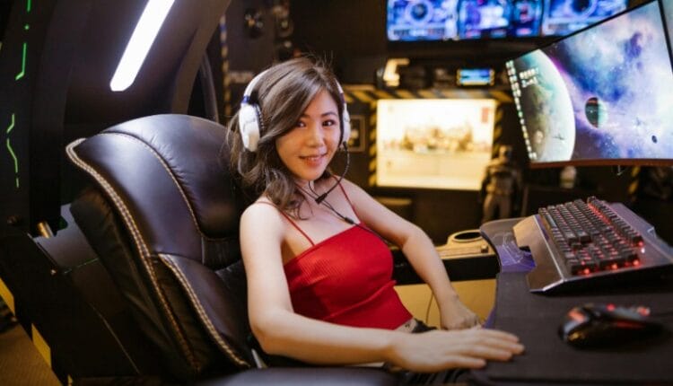 A woman seated at an advanced gaming setup featuring a scorpion gaming chair, multiple monitors, and gaming peripherals., tags: hinter die - pexel