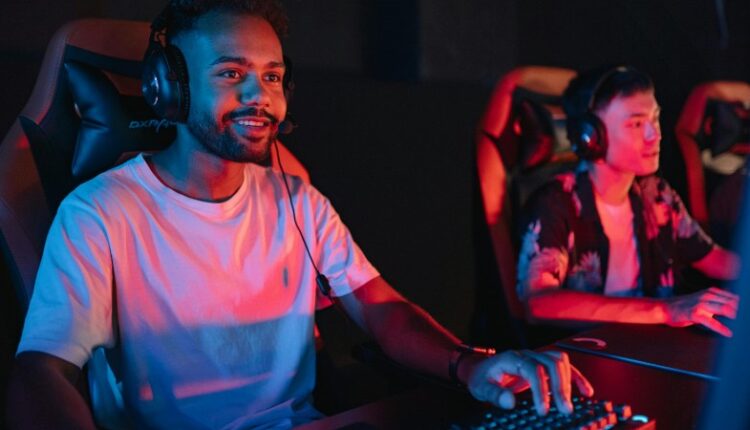 Two male gamers intensely focused during a gaming session in a cybercafe with colorful lighting., tags: spielhallen - pexel